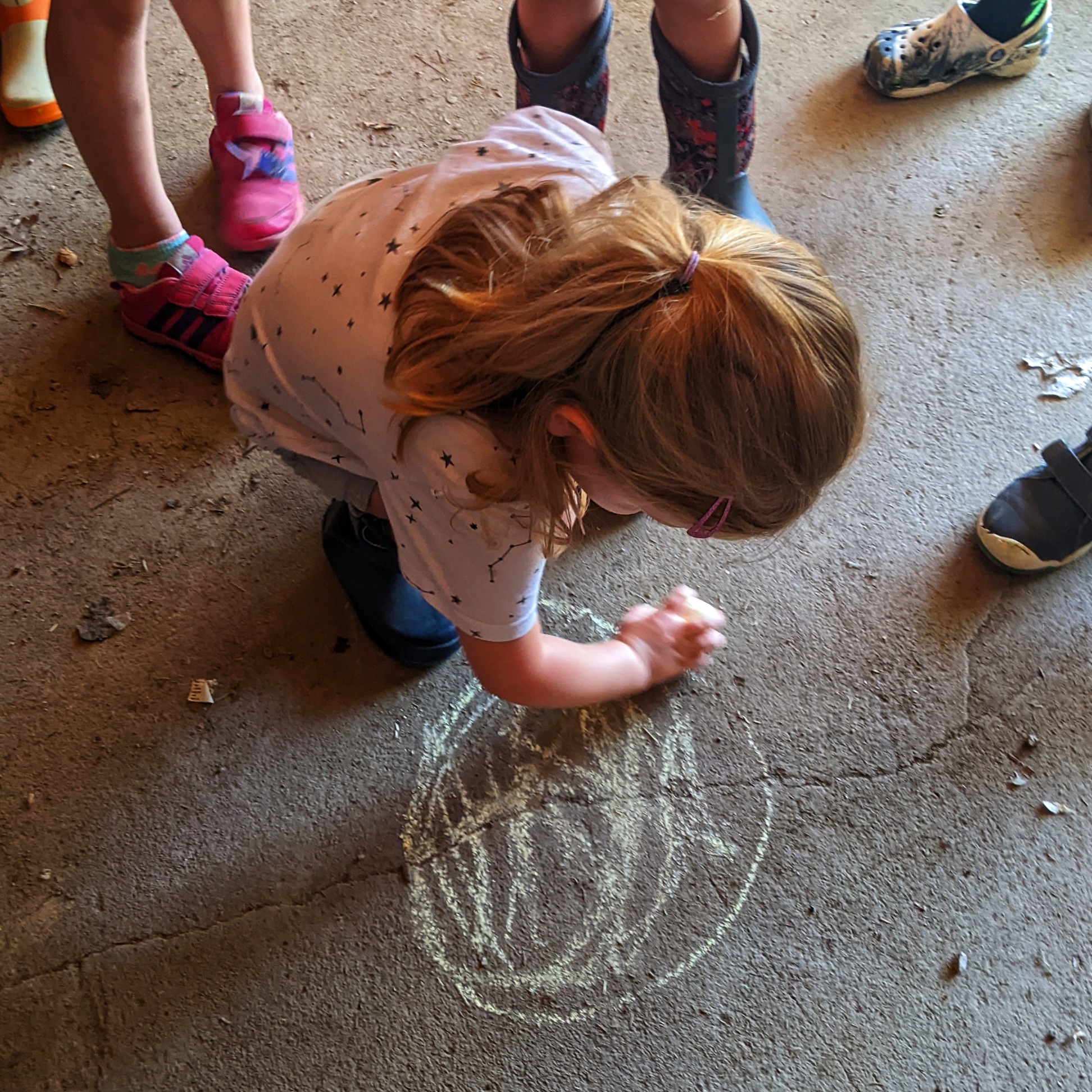 Girl drawing a planet with sidewalk chalk