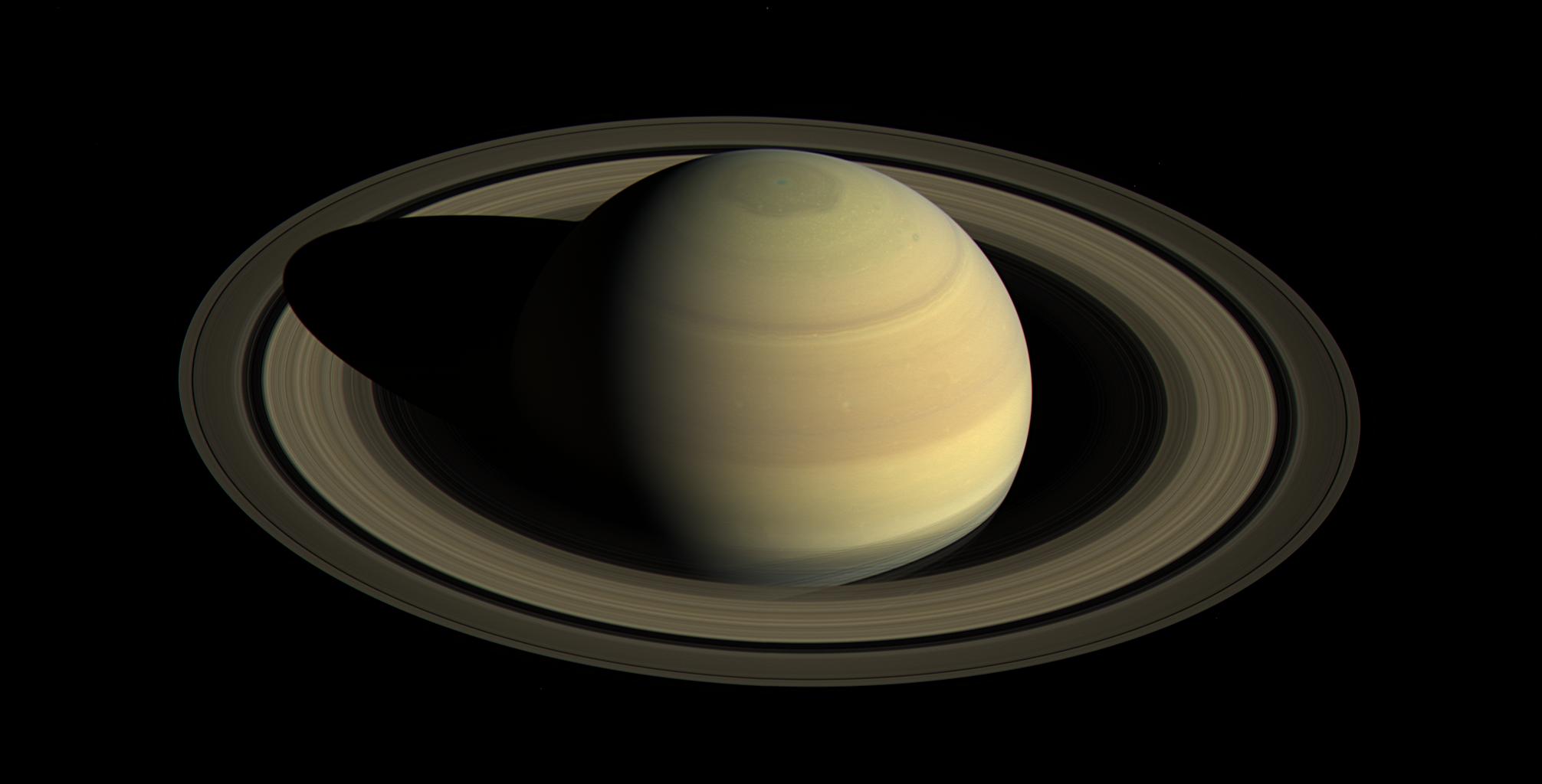 This color view shows all of Saturn with its vast rings extending far into space. The view is from above and the shadow of the planet is visible across the rings.