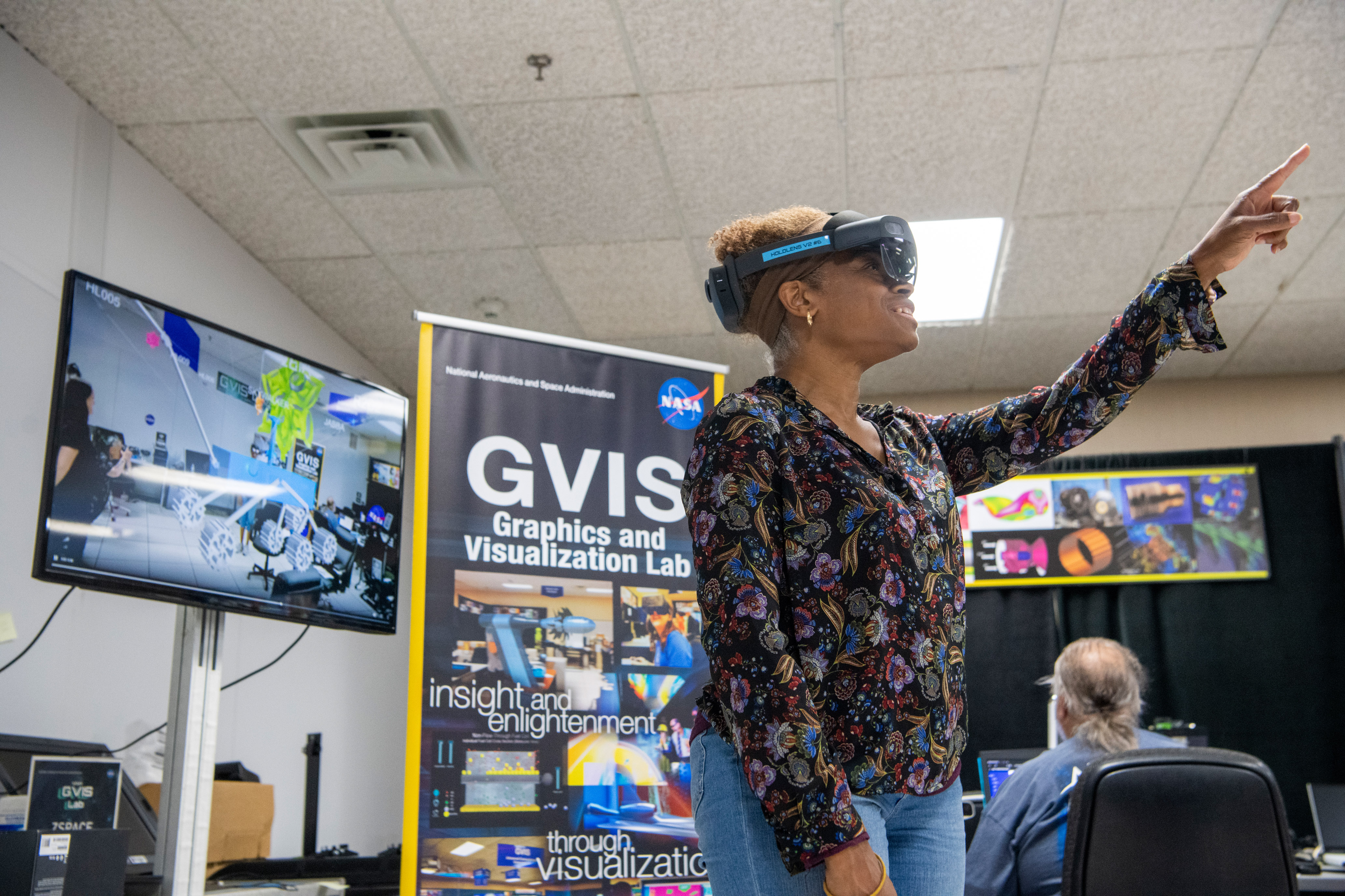 slide 1 - NASA engineer looks through the Microsoft HoloLens to see the spacecrafts the students designed.